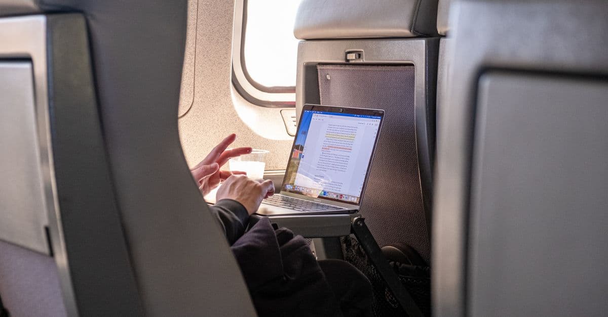 Passenger working on a laptop during flight, highlighting travel productivity.