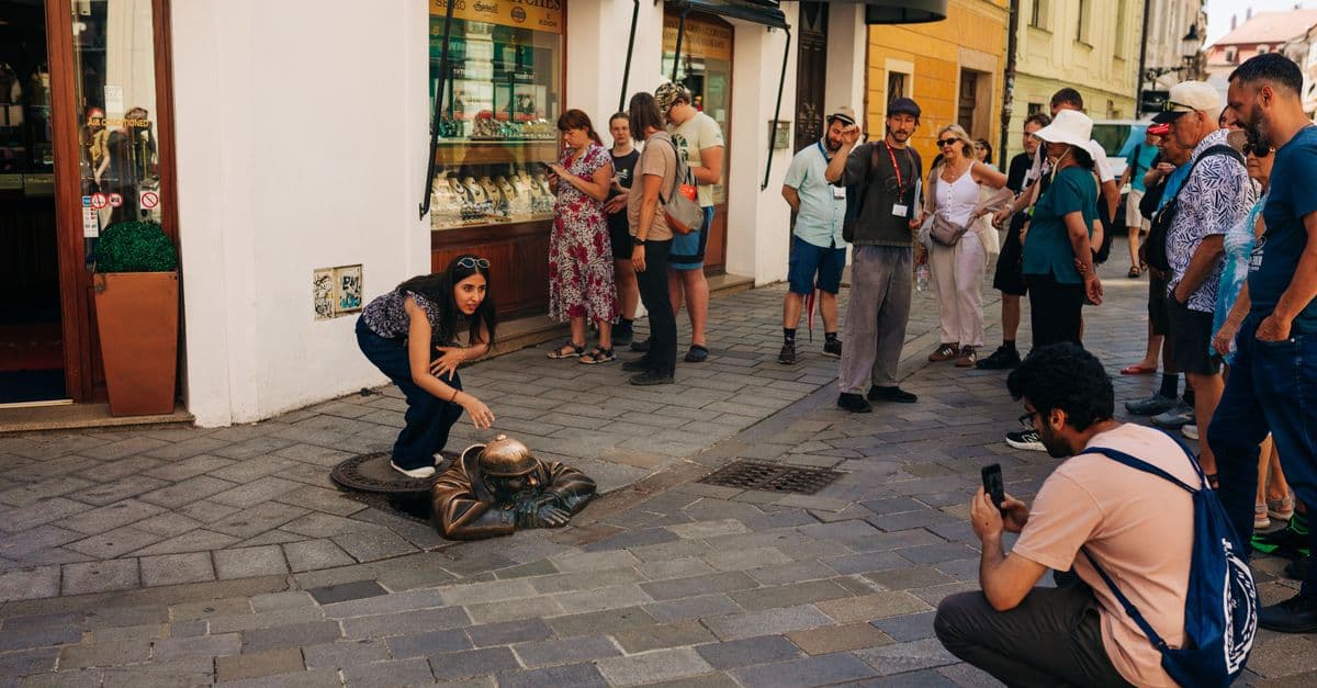Visitors gather around the famous Man at Work statue in Bratislava's streets.