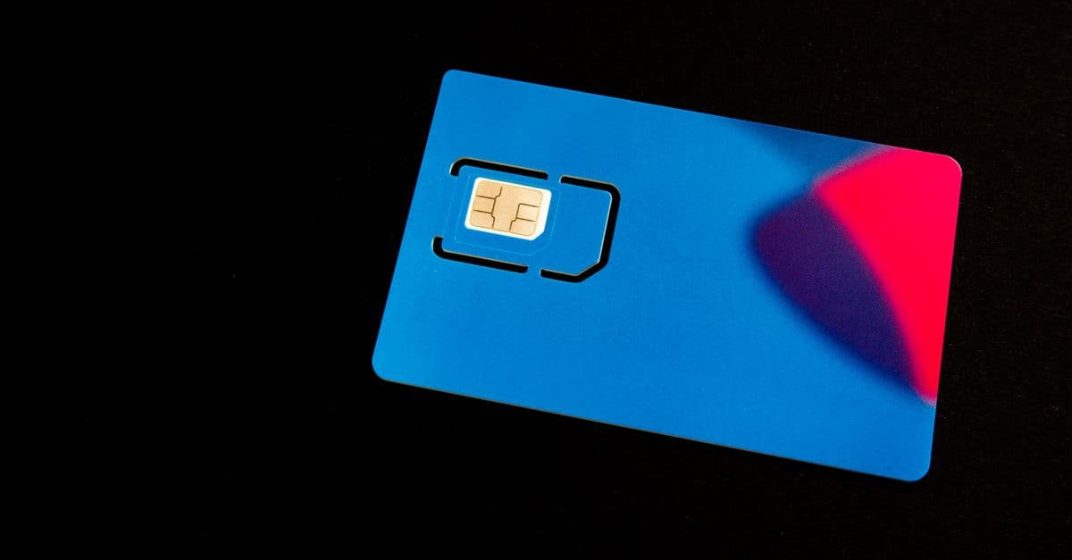 A blue SIM card on a dark background with vibrant red and purple accents.